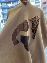 Ruana abierta de lana merino en color beige, con diseño de corte amplio y terminaciones con flecos en el ruedo.