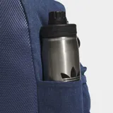 Mochila Adidas de estilo clásico confeccionada en tejido de sarga de algodón color azul denim. Cuenta con un compartimento principal amplio, bolsillo frontal con cierre, bolsillos laterales elásticos y correas ajustables acolchadas con detalle de rayas. Presenta el logotipo del trébol de la marca en la parte inferior frontal.