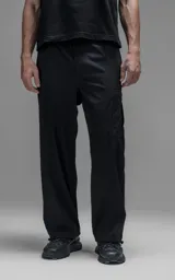 Pantalón cargo de corte oversize confeccionado en microfibra técnica con sutil elasticidad. Presenta cintura elástica, bolsillos laterales y un bolsillo cargo con cierre de broche snap. Incluye un sistema de elásticos con tancas en los tobillos para regular la apertura y la silueta.