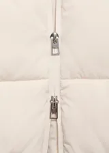 Campera puffer de corte recto y diseño acolchado, color beige. Cuenta con capucha, cuello alto, cierre frontal de cremallera doble y dos bolsillos laterales con cierre. Posee acabado water repellent y puños elásticos.