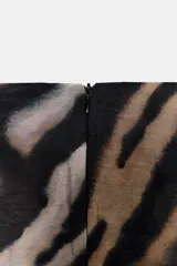 Falda pareo midi de tiro medio con estampado animal print tipo cebra, detalle de nudo drapeado en la parte delantera y abertura frontal. Cuenta con cierre de cremallera en la espalda.