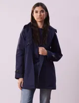 Gabardina color beige, impermeable, con abertura central con botones, bolsillos delanteros, capucha desmontable y forro interno.