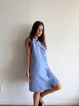Vestido celeste sin mangas con cuello camisero y abotonadura frontal.