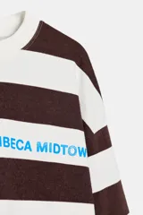 Camiseta de manga larga con cuello redondo y estampado de rayas horizontales en blanco y marrón. Incluye texto azul "TRIBECA MIDTOWN" estampado en el pecho.