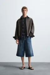 Cazadora bomber de efecto piel color marrón oscuro, con cuello solapa, cierre frontal de cremallera, bolsillos de vivo en cadera y bajo elástico.