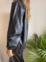 Campera negra de cuero sintético con textura crocco, cierre frontal con cremallera y cuello camisero.