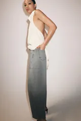Jeans de tiro medio con diseño de pierna tipo balloon y largo al tobillo. Presenta cinco bolsillos, cierre frontal con cremallera y botón, y un acabado con efecto lavado.