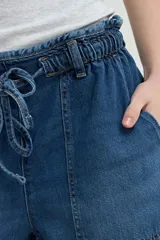 Short de denim azul con cintura elastizada fruncida, cordón de ajuste y bolsillos delanteros parcheados.