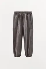 Pantalón bombacho de tiro medio con estampado de rayas verticales finas. Presenta cintura elástica con cordón ajustable, bolsillos laterales, costuras decorativas marcadas y bajo abullonado con elástico.