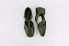 Zapatos bajos color verde oliva de cuero, con tira sobre el empeine y hebilla dorada.