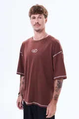 Remera de corte boxy color marrón, con costuras a la vista en color blanco, cuello redondo y pequeño logo bordado en el centro del pecho.