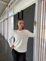 Remera blanca de manga larga con cuello redondo y bordado floral en el pecho.