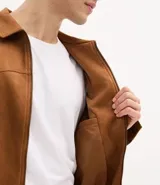Campera masculina de estilo casual con cuello inglés, cierre frontal por cremallera, bolsillos laterales y ajuste elástico en el bajo. Presenta detalles de recortes en la parte superior delantera.