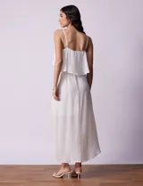 Vestido midi blanco de gasa bambula marca Lily Black, con escote redondo, breteles regulables y lazo de ajuste. Presenta una sobrecapa en el torso y un forro interno a tono. El largo de la espalda es mayor al largo delantero.