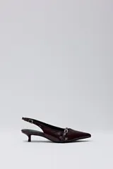 Zapato tipo slingback en color bordó, con punta fina, taco bajo y detalle de tira con hebilla metálica sobre el empeine.