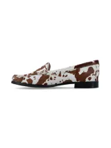 Mocasines de cuero con pelo, con estampado de manchas tipo vaca en tonos marrón y blanco. Presentan un diseño clásico de mocasín con antifaz y suela plana de goma negra.