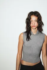 Chaleco de punto color blanco, estilo polo, sin mangas (manga sisa) y cuello solapa. La parte inferior termina en rib.