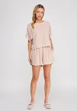 Blusa corta de lino y viscosa color beige, con escote redondo, mangas cortas holgadas tipo mariposa y detalles de bordado festoneado en contrastes blancos en el cuello, puños y ruedo.
