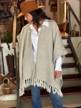 Ruana de lana merino color beige con diseño geométrico en zigzag y flecos en el ruedo.
