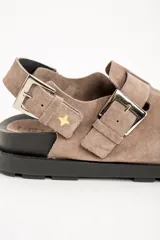 Zueco color visón de cuero con hebillas plateadas y suela negra.