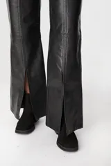 Pantalón de cuero color chocolate con efecto desgastado, de corte recto y tiro medio. Presenta costuras verticales en el frente y tajos laterales en el ruedo que aportan movimiento.
