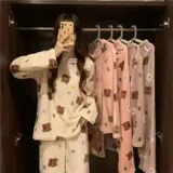 Conjunto de pijama de dos piezas confeccionado en plush suave, compuesto por una remera de manga larga y pantalón largo. Presenta un diseño estampado de duraznos sobre fondo color crema.