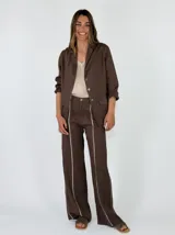 Blazer de lino color marrón con solapa clásica, cierre frontal de tres botones, bolsillos aplicados con solapa y costuras pespunteadas en contraste.