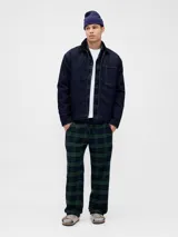 Conjunto de pijama para hombre compuesto por una camisa de manga larga con botones y un pantalón largo, ambos confeccionados en tela de franela con estampado de cuadros en tonos verde y azul marino.