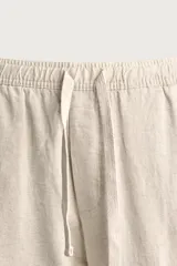 Pantalón de corte relajado confeccionado en una mezcla de algodón y lino. Presenta cintura elástica con cordón ajustable, bolsillos laterales y bolsillos traseros de vivo.