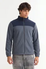Campera de polar con cierre frontal completo, cuello alto y diseño de bloques de color en azul marino y gris. Cuenta con bolsillos laterales y puños elásticos.