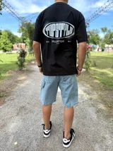 Remera negra de corte oversize con estampado gráfico en la espalda que dice "TOPSTYLE COLLECTIONS".