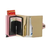 Billetera tarjetero automática con estructura de aluminio y revestimiento de cuero bicolor en tonos verde oliva y beige. Cuenta con un cierre de broche a presión y el logo de la marca grabado en la parte inferior.