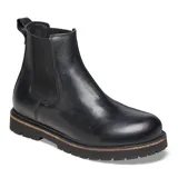 Botas Chelsea negras de cuero liso, con paneles elásticos laterales, tirador trasero y suela gruesa de goma con detalle de vira en color madera.