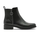 Bota corta de cuero negro con cierre lateral metálico que incluye un dije circular con la letra K. Presenta un diseño minimalista con taco bajo cuadrado y suela de goma.