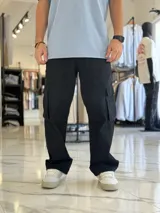 Pantalón cargo de jean negro, de corte holgado y diseño oversize, con múltiples bolsillos utilitarios en los laterales y muslos.
