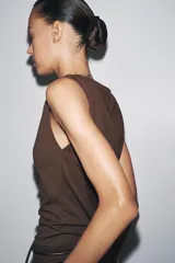 Top de tejido punto color marrón oscuro, con escote asimétrico tipo *one-shoulder* y drapeado frontal.