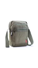 Morral de tela canvas color verde militar con detalles en cuero sintético. Presenta un compartimento principal con cierre superior, dos bolsillos frontales con cremallera y un bolsillo trasero. Incluye una correa de hombro ajustable y etiqueta de marca lateral.