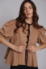 Chaqueta o blusa de tejido natural color verde menta, con mangas balloon y un botón decorativo en forma de estrella de mar. El cuerpo tiene un ruedo evasé.