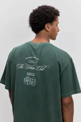 Remera de algodón color verde oscuro, de corte holgado y manga corta, con pequeño estampado gráfico en el pecho.