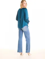 Blusa de satén color verde azulado con acabado sedoso y fluido. Escote a la base con frunce perimetral, mangas largas estilo balloon con detalle de punto smock en hombros y puños. Espalda con abertura tipo gota y botón forrado a tono.