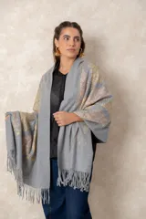 Pashmina de tela densa y suave, con caída pesada y diseño de patrones bordados en hilos dorados y beige. Presenta terminaciones con flecos en los extremos.