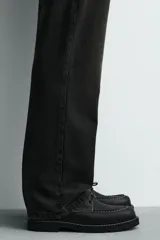 Zapato de cordones tipo derby, color negro, con capellada de cuero, horma redonda y suela con volumen. Presenta detalle de pespuntes blancos a contraste.