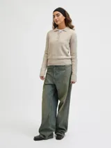 Sweater de punto color beige, con cuello polo y cierre frontal de tres botones, mangas largas con puños acanalados y diseño clásico.