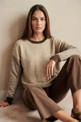 Sweater de tejido de punto con diseño color block en tonos beige y marrón. Presenta cuello redondo, mangas largas con puños acanalados y un ajuste al cuerpo.