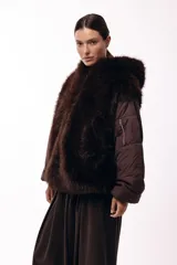 Campera de invierno con frente de piel sintética y capucha integrada, combinada con mangas acolchadas de estilo puffer en color marrón oscuro.