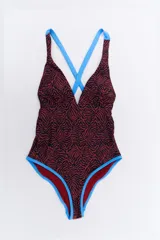 Malla enteriza con estampado animal print tipo cebra en tonos bordó y negro, con breteles cruzados en la espalda y bordes en color celeste.