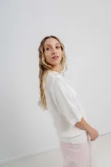 Buzo de tejido abierto color beige claro, de calce oversize con mangas 3/4 y cuello redondo. Presenta terminaciones acanaladas en puños y cintura.