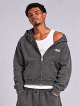 Campera estilo boxy color gris con efecto lavado, confeccionada en algodón. Cuenta con cierre frontal entero, capucha ajustable, bolsillos tipo canguro y el logo de la marca estampado en el pecho.