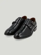 Zapato de vestir de cuero color negro, con diseño de doble hebilla lateral y suela de cuero.