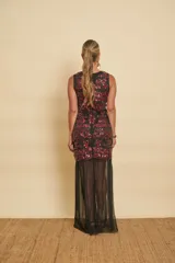 Vestido largo negro con apliques de lentejuelas rojas en el cuerpo y una falda inferior semitransparente de tul.